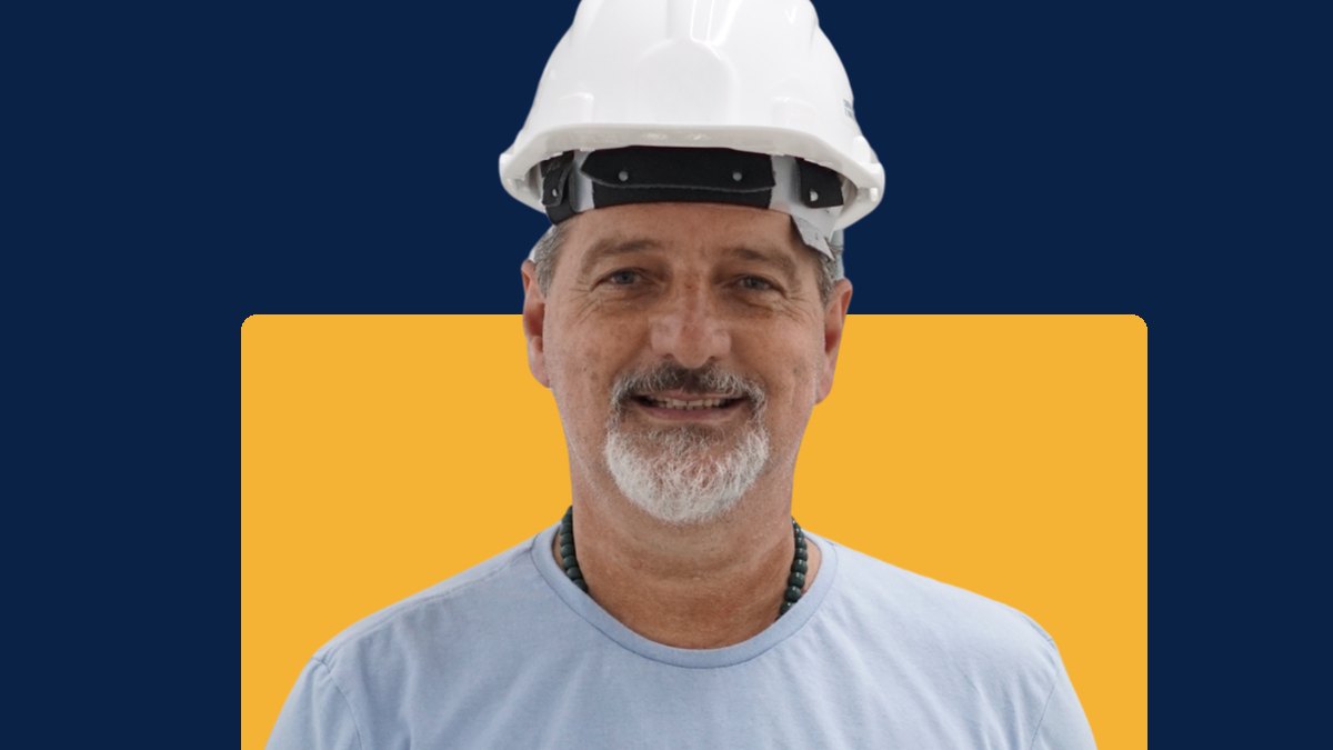 Joa de capacete branco, sorrindo de frente para a câmera